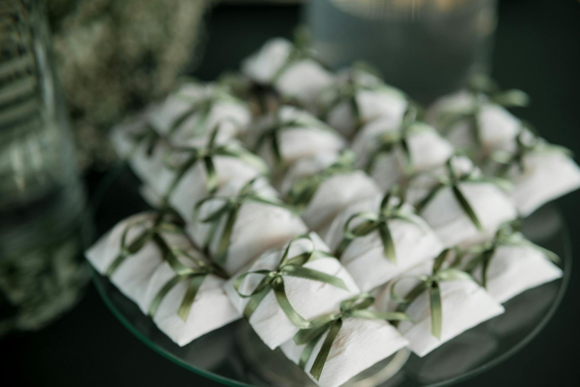 Białe pudełka prezentowe z zielonymi wstążkami jako elegancki upominek ślubny