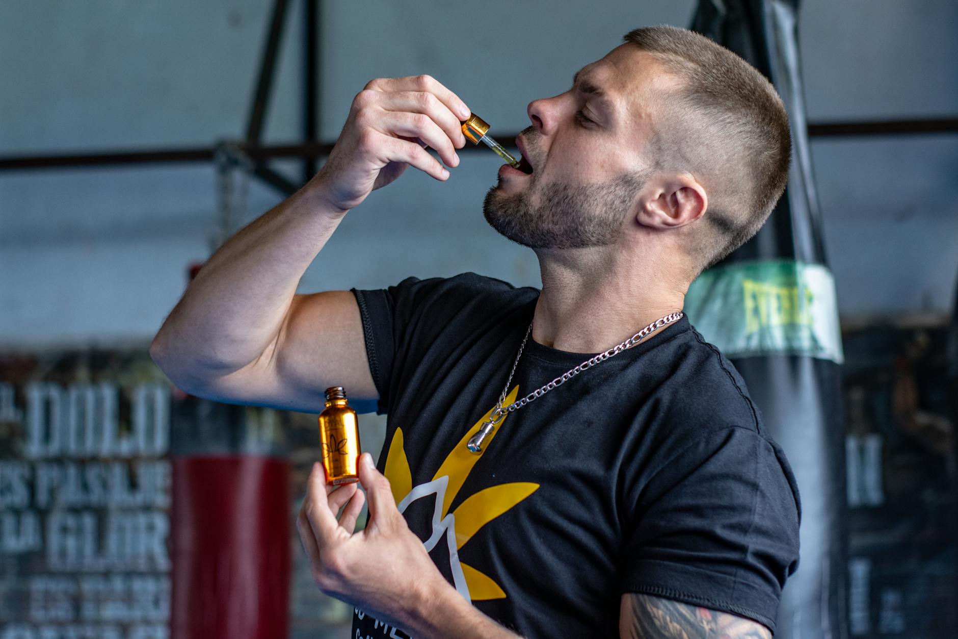 Mężczyzna w siłowni przyjmuje olejek CBD z pipety