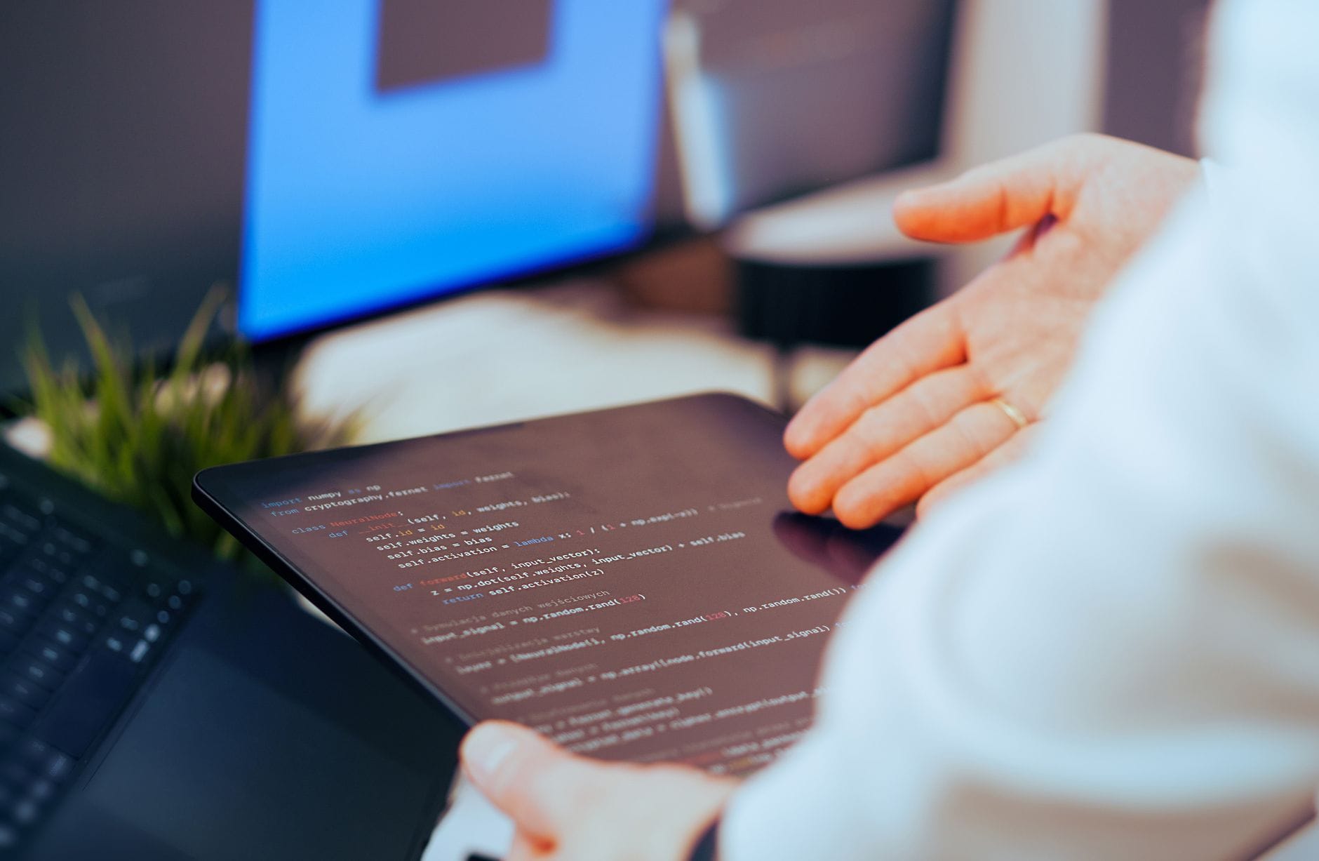 Najlepsze programy do tworzenia AI w 2025 roku: porównanie narzędzi dla początkujących i profesjonalistów Programista analizujący kod na tablecie w nowoczesnym biurze